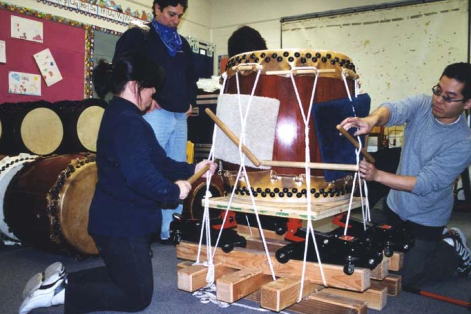 Three people stand around a stretching rig tightening the tension
